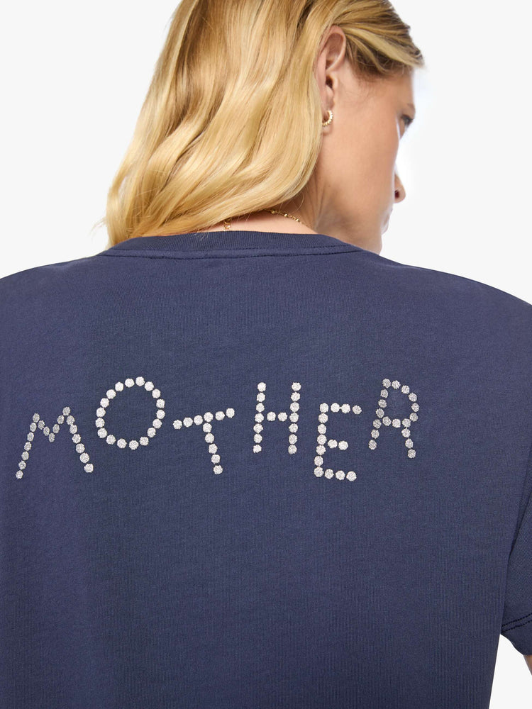 Back close up view of a woman in dark navy tee with a faded text graphic in white on the front, rhinestone details and MOTHER's name in studs on the back.