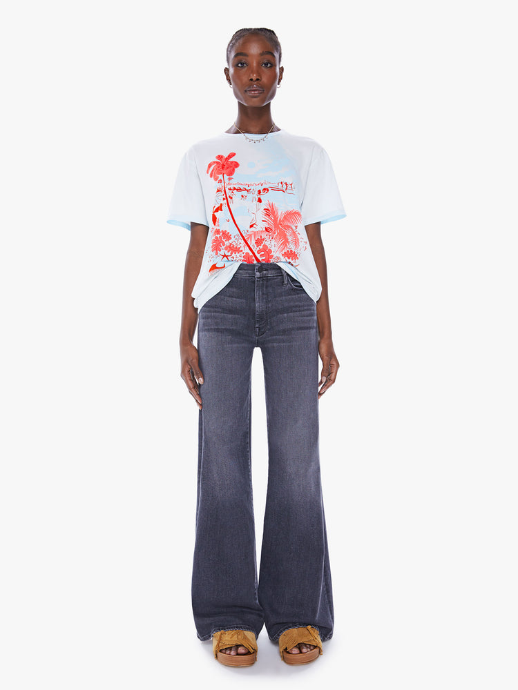 Full body view of a woman crewneck tee with an oversized fit in a semi-sheer off-white tee features a bright red graphic.