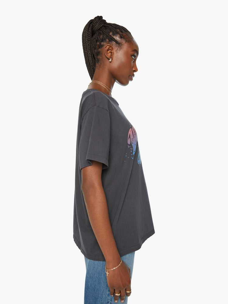 Side view of a woman crewneck tee with an oversized fit in dark grey tee features a blue and pink text graphic on the front.