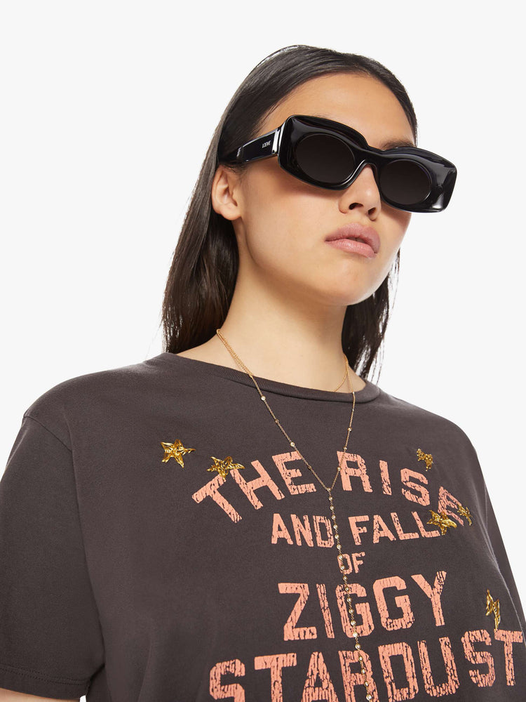 Front close up view of a womens crew neck tee in a faded black, featuring a David Bowie graphic and embroidered gold stars.