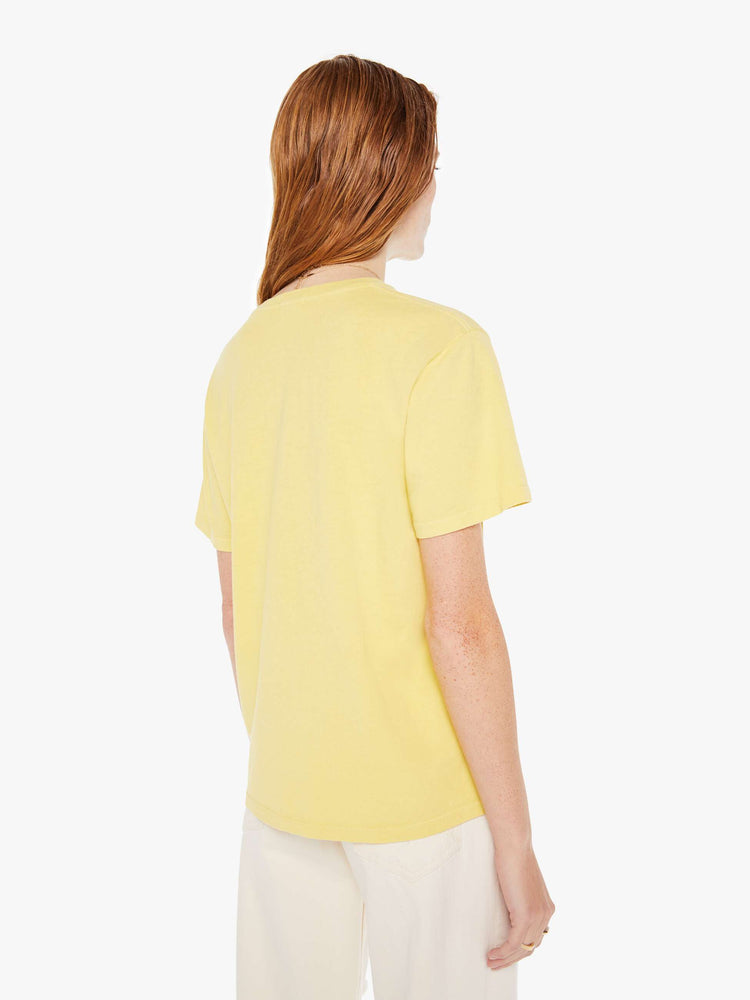 A back view of a woman wearing a faded yellow oversized crew neck tee, paired with off white jeans.