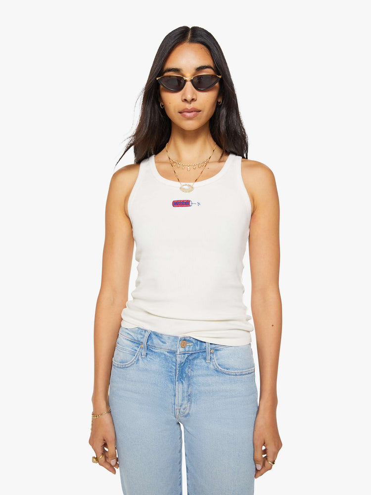 Front view of a woman in a white with fire cracker tank with wide straps and a slightly shrunken fit.