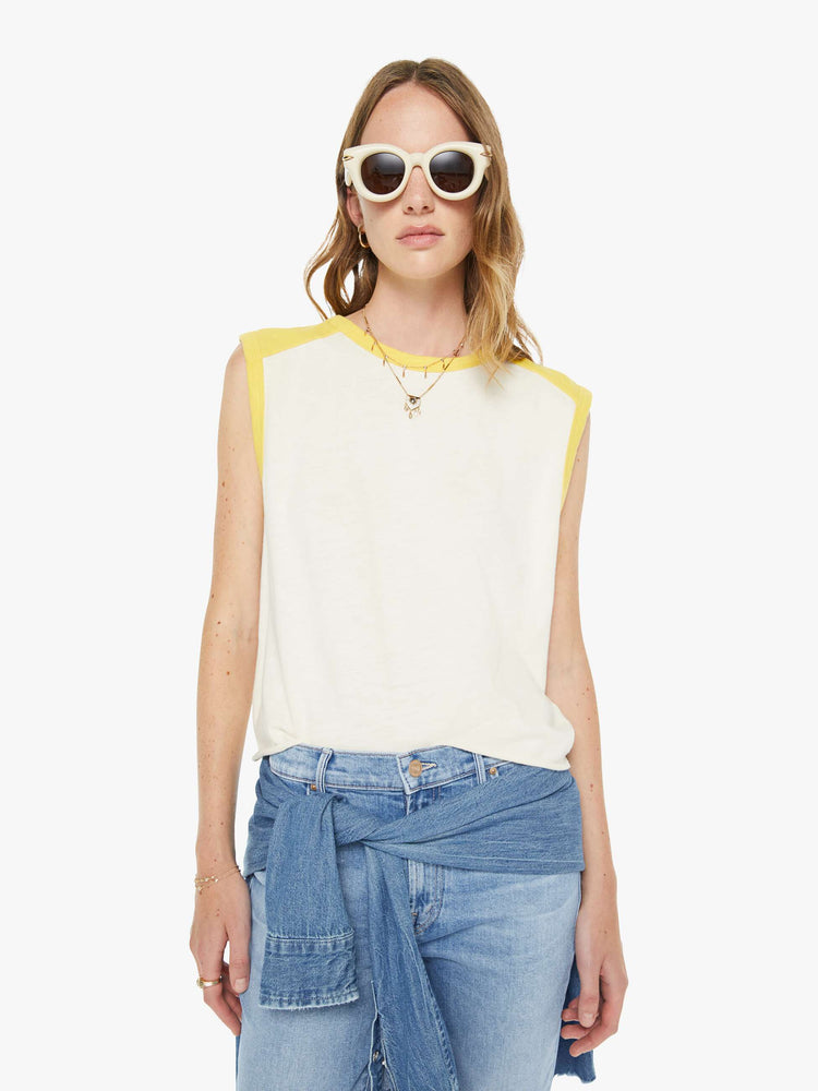 Front view of a woman in an off-white  tee with cutoff sleeves and a raw hem. 
