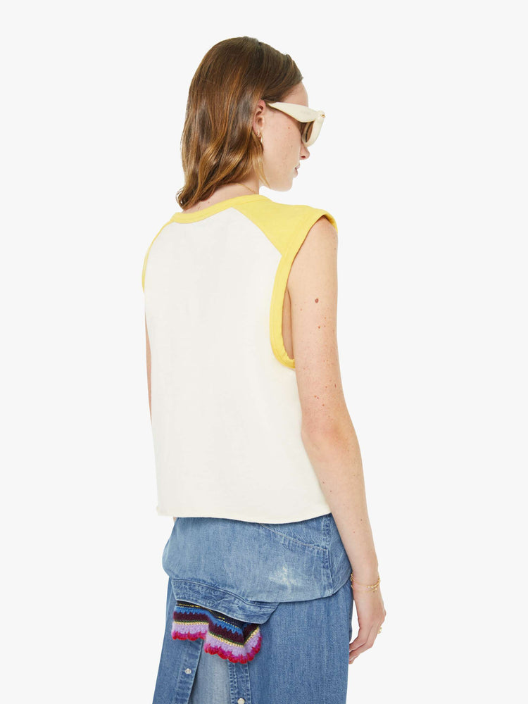 Back view of a woman in an off-white  tee with cutoff sleeves and a raw hem. 