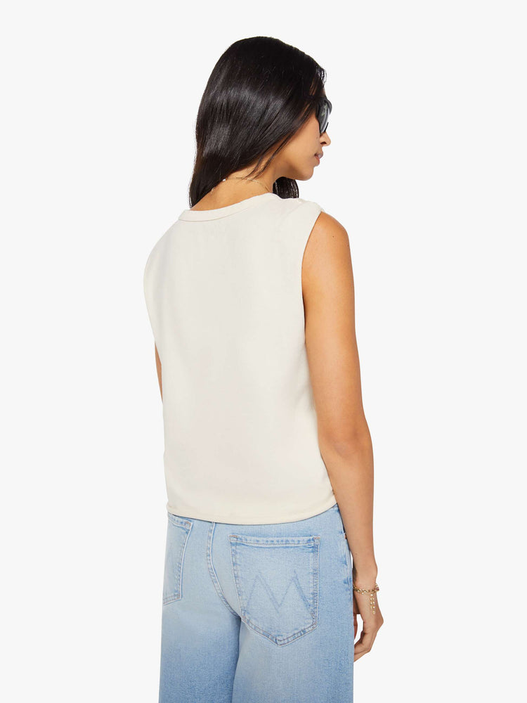 Back view of a woman in a off white sleeveless tee with a crewneck, knotted detail on one shoulder, an oversized fit and a raw hem.