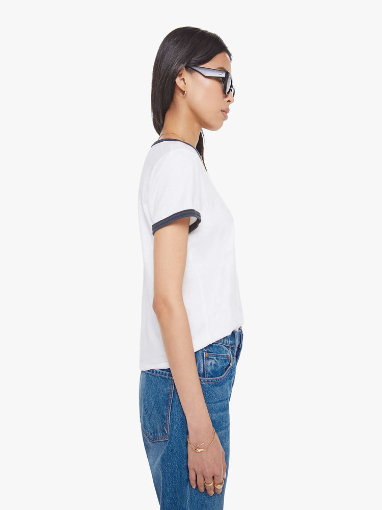 Side view of a woman in a white tee with navy trim, the tee features MOTHER's name on the front.
