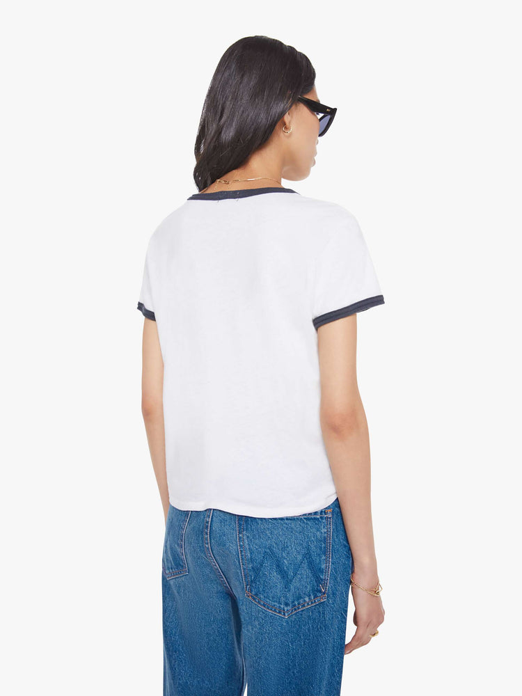 Back view of a woman in a white tee with navy trim, the tee features MOTHER's name on the front.