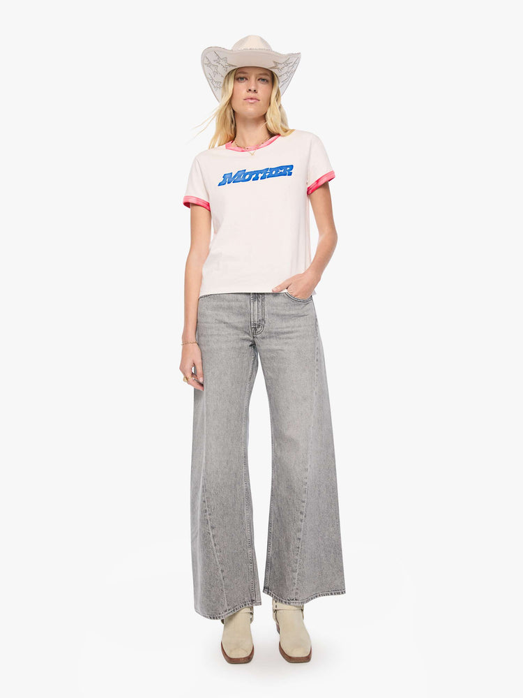 Full body view of a woman in a white tee with sun-faded red trim extra-short sleeves and a slightly shrunken fit with a flocked MOTHER graphic across the chest.