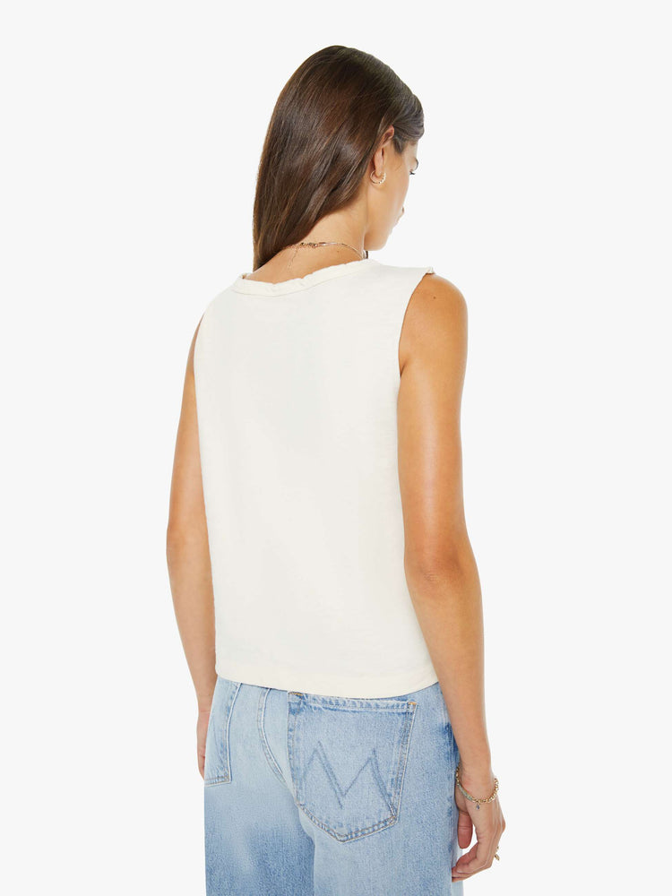 Back view of a woman in an off-white top features a campfire graphic with text in pink on the front cut off sleeveless top.