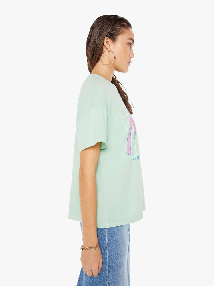 Side view of a woman wearing a light teal crew neck tee with an oversized fit, featuring a retro inspired graphic that reads "Mother".
