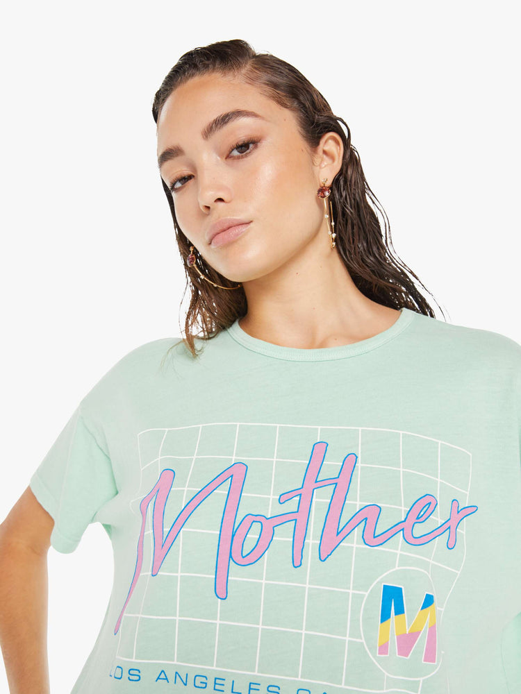 Front close up view of a woman wearing a light teal crew neck tee with an oversized fit, featuring a retro inspired graphic that reads "Mother".