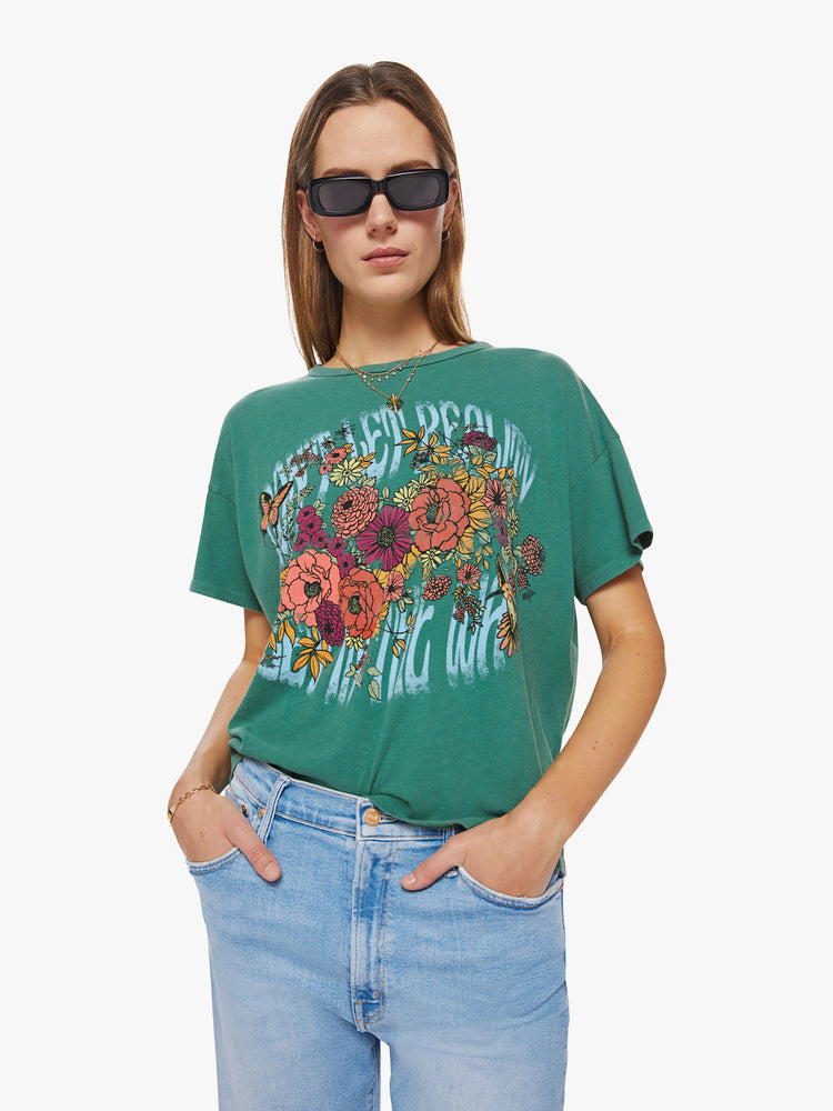 Front view of a woman oversize tee with drop shoulders and a loose, boxy fit in a washed green hue with trippy graphic text and flowers.