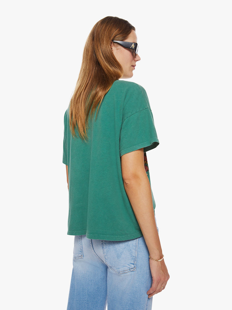 Back view of a woman oversize tee with drop shoulders and a loose, boxy fit in a washed green hue with trippy graphic text and flowers.