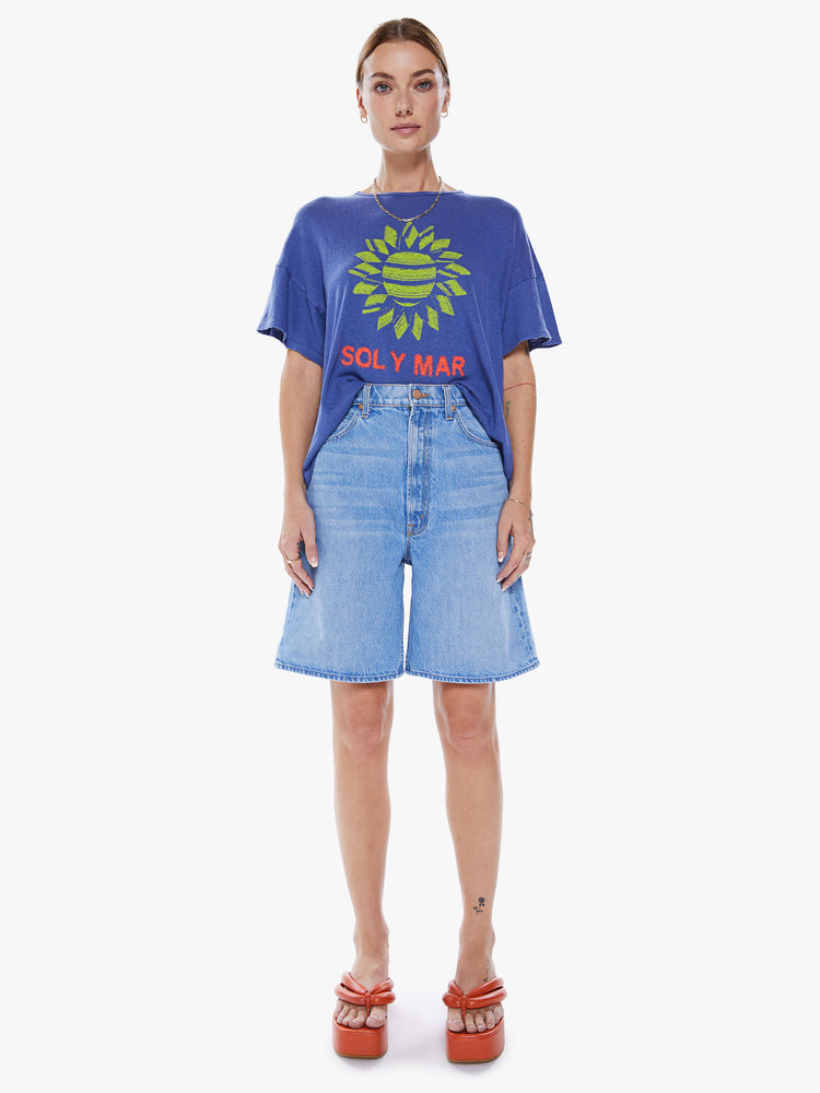 Full body view of a women's blue oversized tee with drop shoulders and a loose, boxy fit with a green sun graphic and text in red.