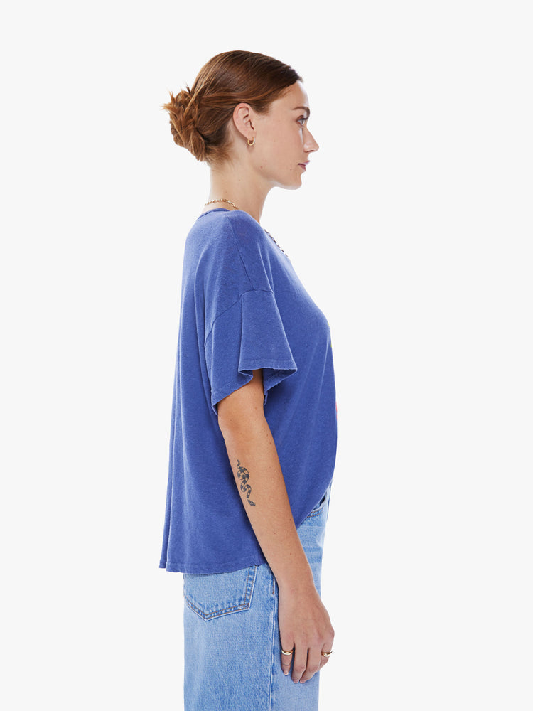 Side view of a women's blue oversized tee with drop shoulders and a loose, boxy fit with a green sun graphic and text in red.