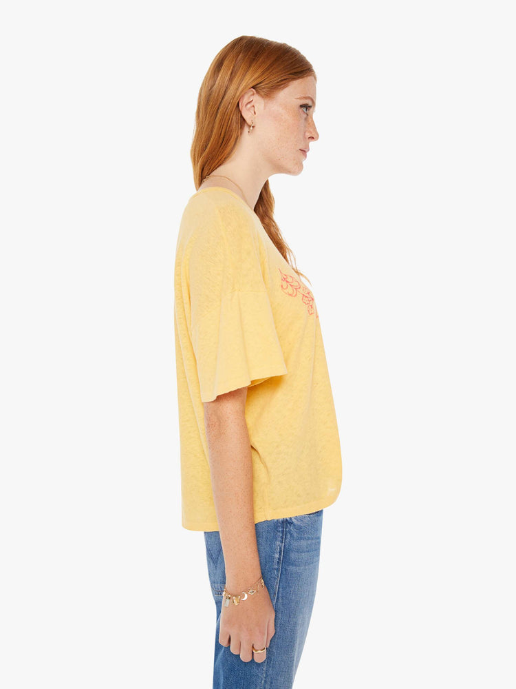 Side view of a womens yellow crew neck tee featuring an oversized fit and a pink graphic reading "MOTHER".
