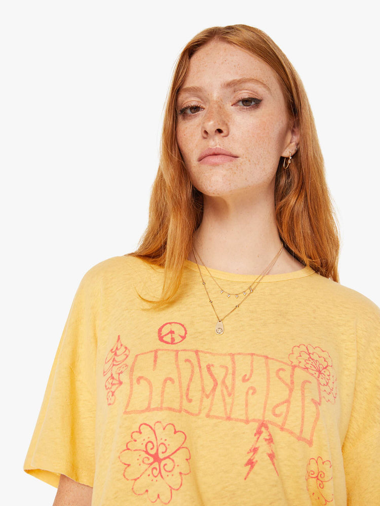 Front close up view of a womens yellow crew neck tee featuring an oversized fit and a pink graphic reading "MOTHER".