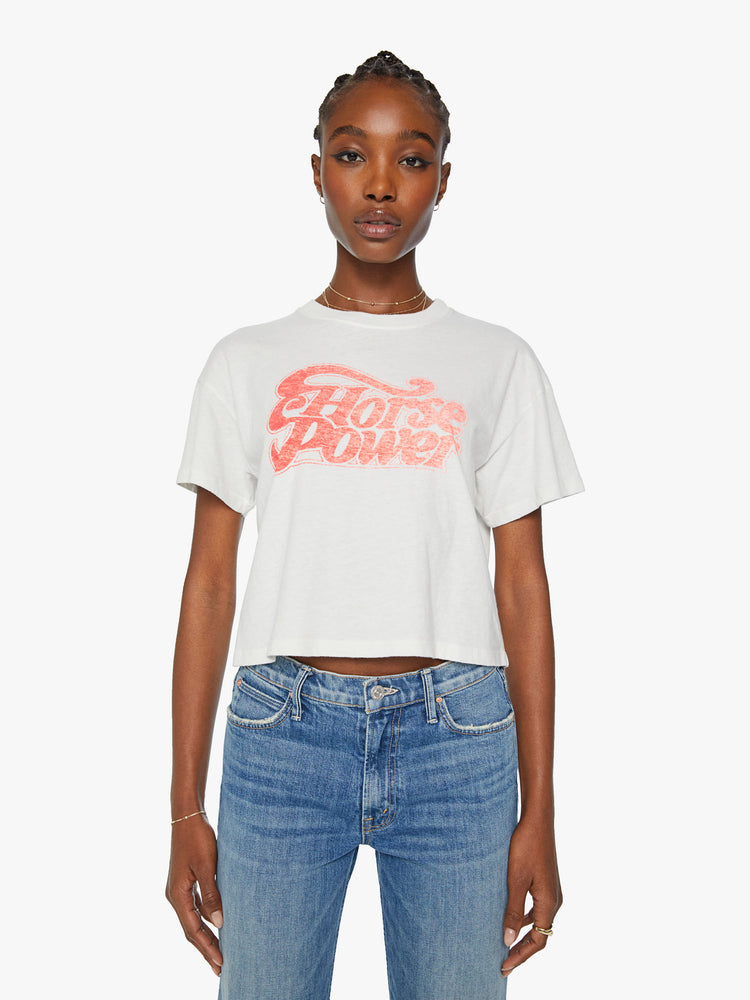 Front view of a woman oversized crewneck tee with a cropped hem in an off white with a peach graphic in front.