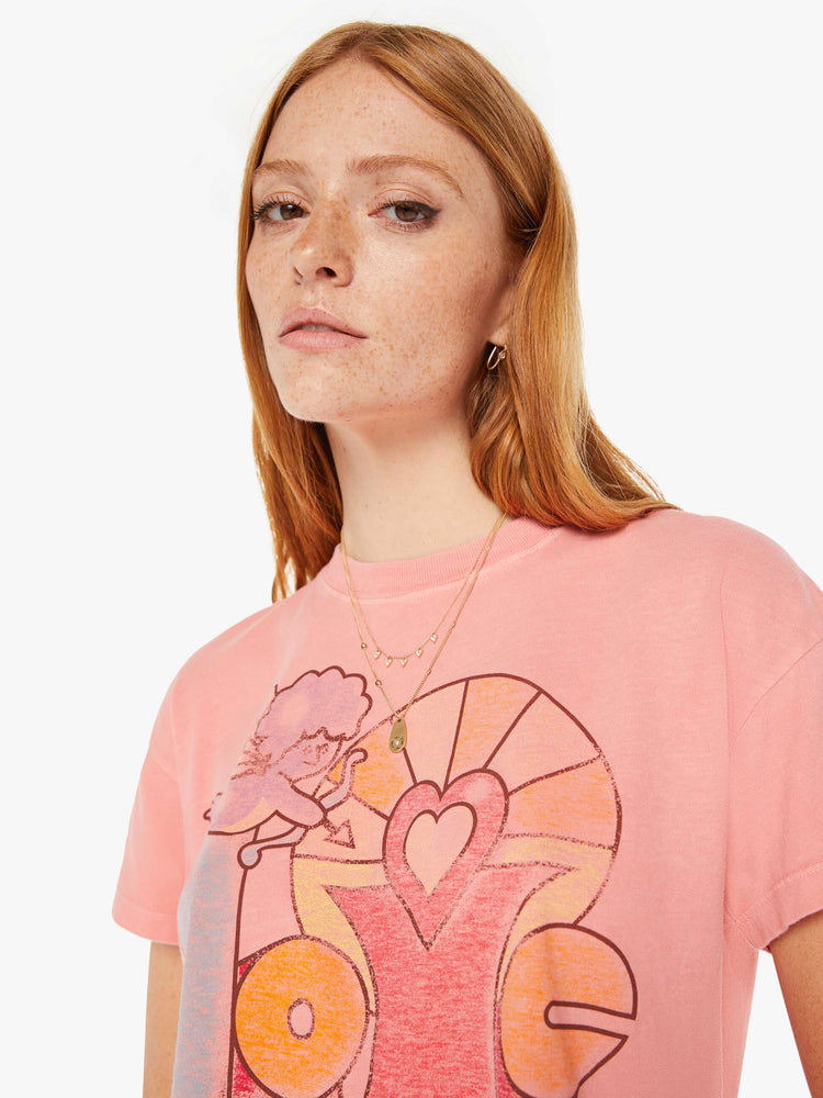 Front close up view of a womens pink crew neck tee featuring a cropped body and a LOVE with Cupid graphic.