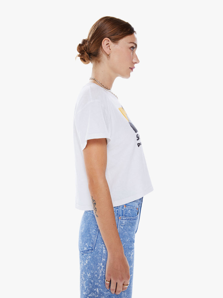 Side view of a woman crewneck tee with drop shoulders, a cropped hem and a boxy fit in a white hue with colorful tourist graphic.