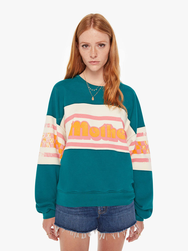 Front view of a womens oversized crew neck sweatshirt in teal featuring a striped graphic reading "MOTHER".