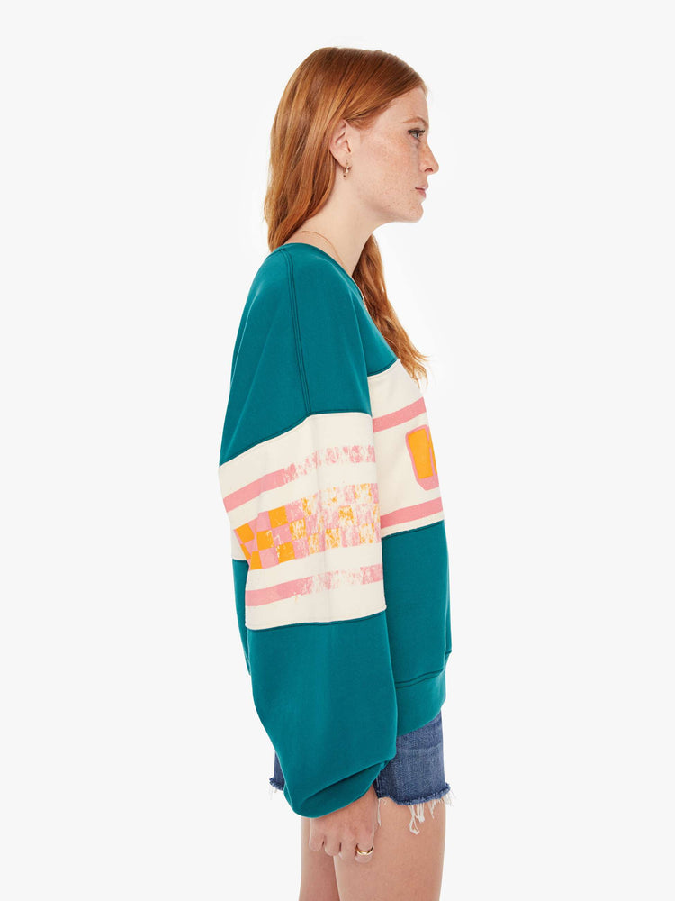 Side view of a womens oversized crew neck sweatshirt in teal featuring a striped graphic reading "MOTHER".
