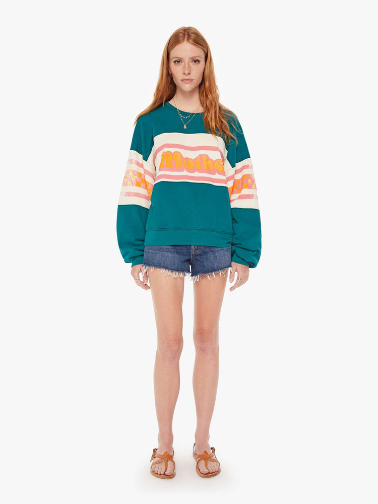 Front full body view of a womens oversized crew neck sweatshirt in teal featuring a striped graphic reading "MOTHER".