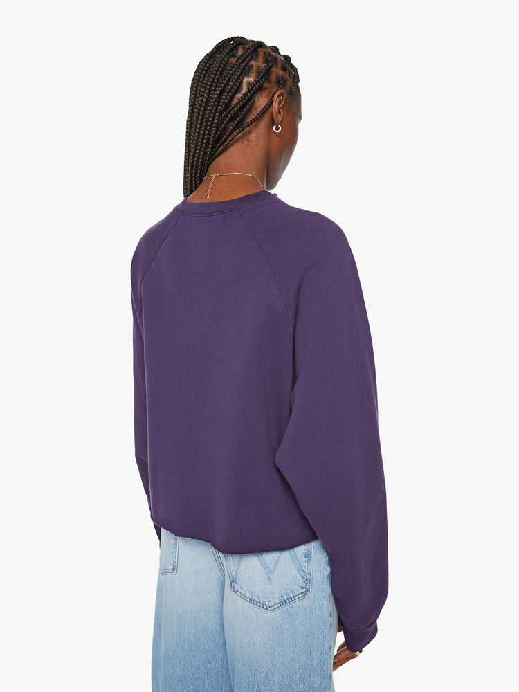 Back view of a woman's cropped sweatshirt with a crew neck, drop shoulders and a raw hem in dark purple.