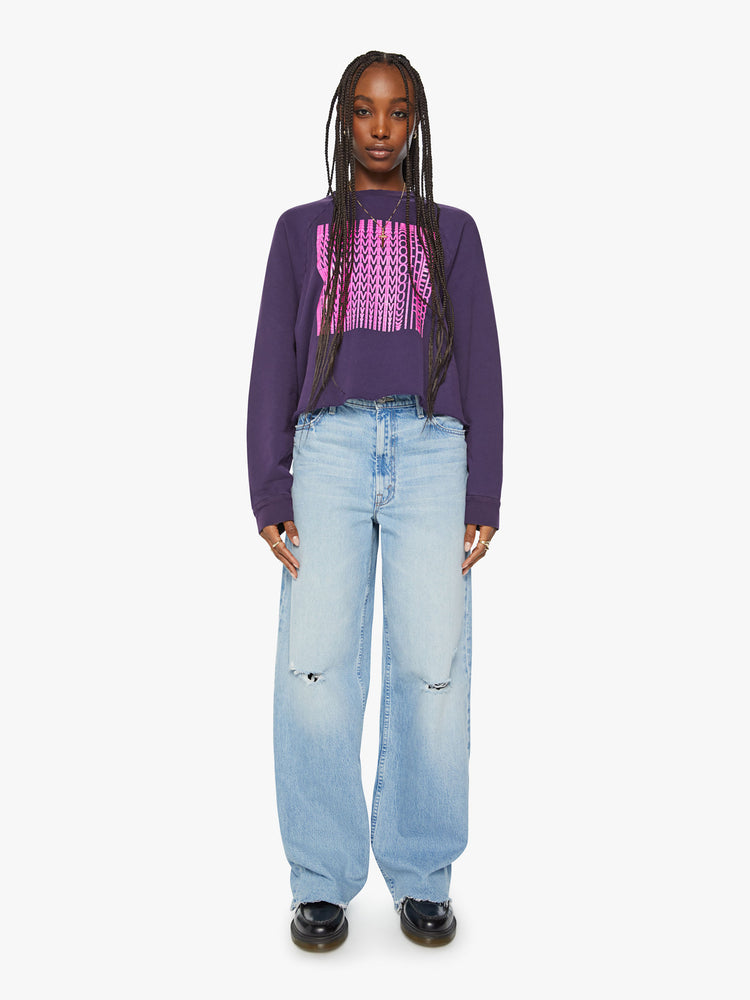 Full body view of a woman's cropped sweatshirt with a crew neck, drop shoulders and a raw hem in dark purple.