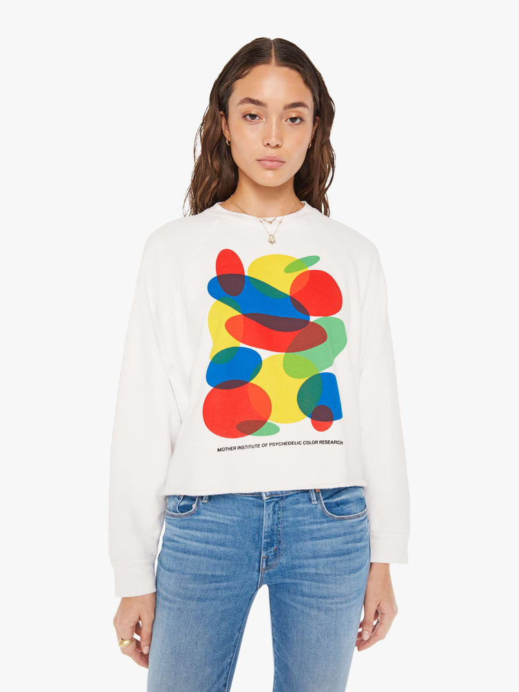 Front view of a woman cropped sweatshirt with a crew neck, drop shoulders and a raw hem in white with an overlapping abstract graphic and text in black on the front.