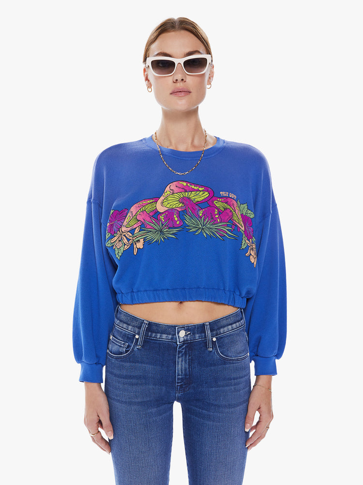 Front view of a women blue crewneck sweatshirt with dropped sleeves, a relaxed fit and a cropped elastic hem with a neon mushroom graphic and some subtle advice.
