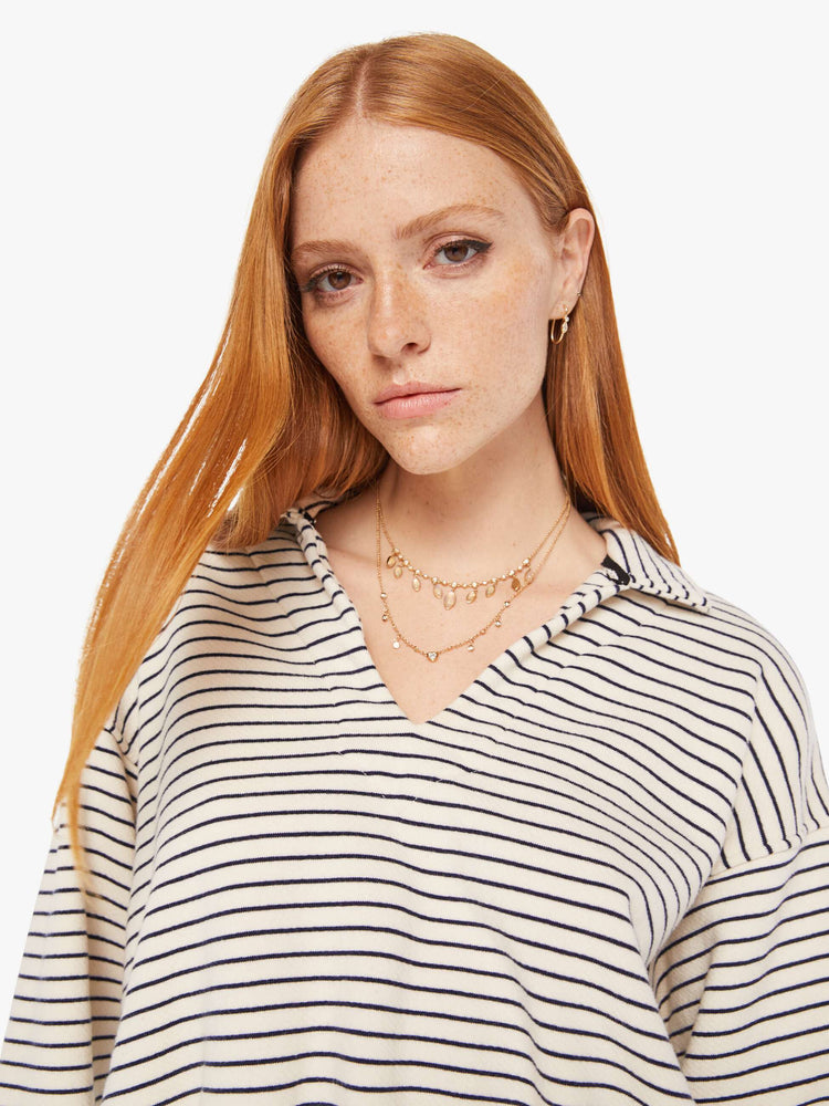 Front close up view of a womens black and white striped pullover featuring an opened collar and a cropped, cinched waist.