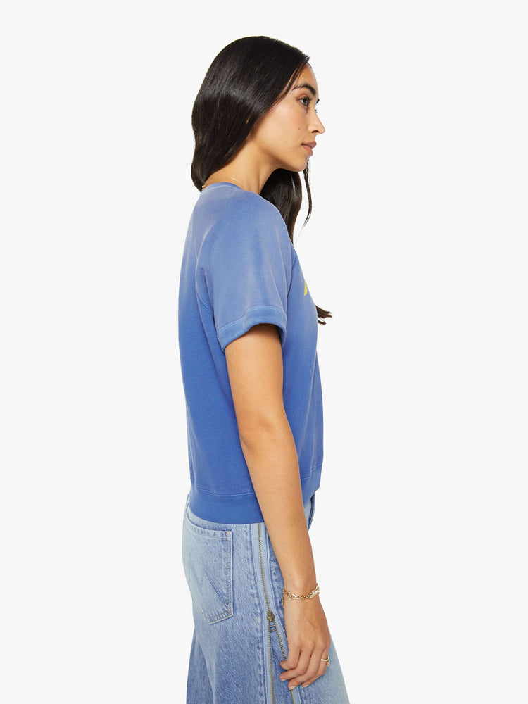 Side view of a woman in a blue with fading across the chest and shoulders and MOTHER's name in crackle-printed yellow text on the front short sleeve sweatshirt.