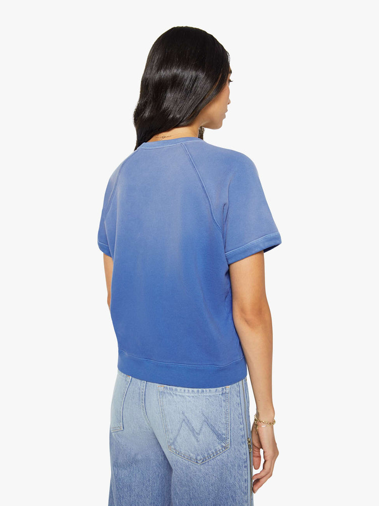 Back view of a woman in a blue with fading across the chest and shoulders and MOTHER's name in crackle-printed yellow text on the front short sleeve sweatshirt.