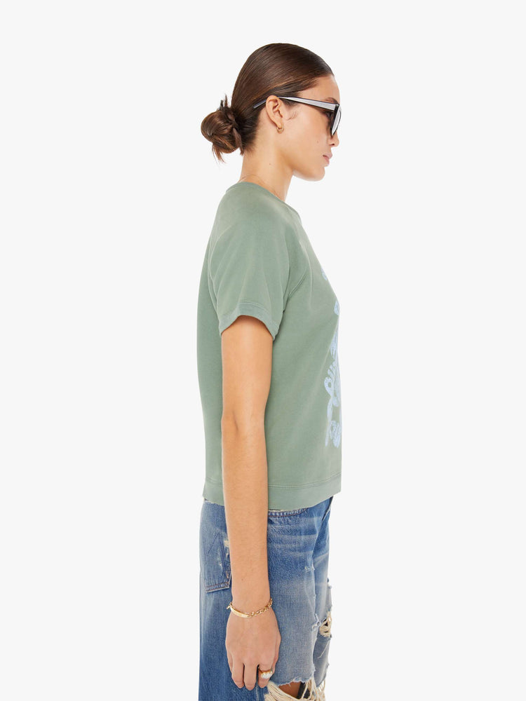 Side view of a womens faded green crew neck short sleeve sweatshirt featuring a light blue graphic.