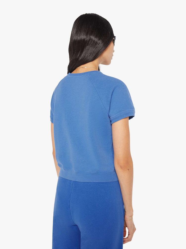 Back view of a woman in blue with white wording short-sleeve raglan sweatshirt.