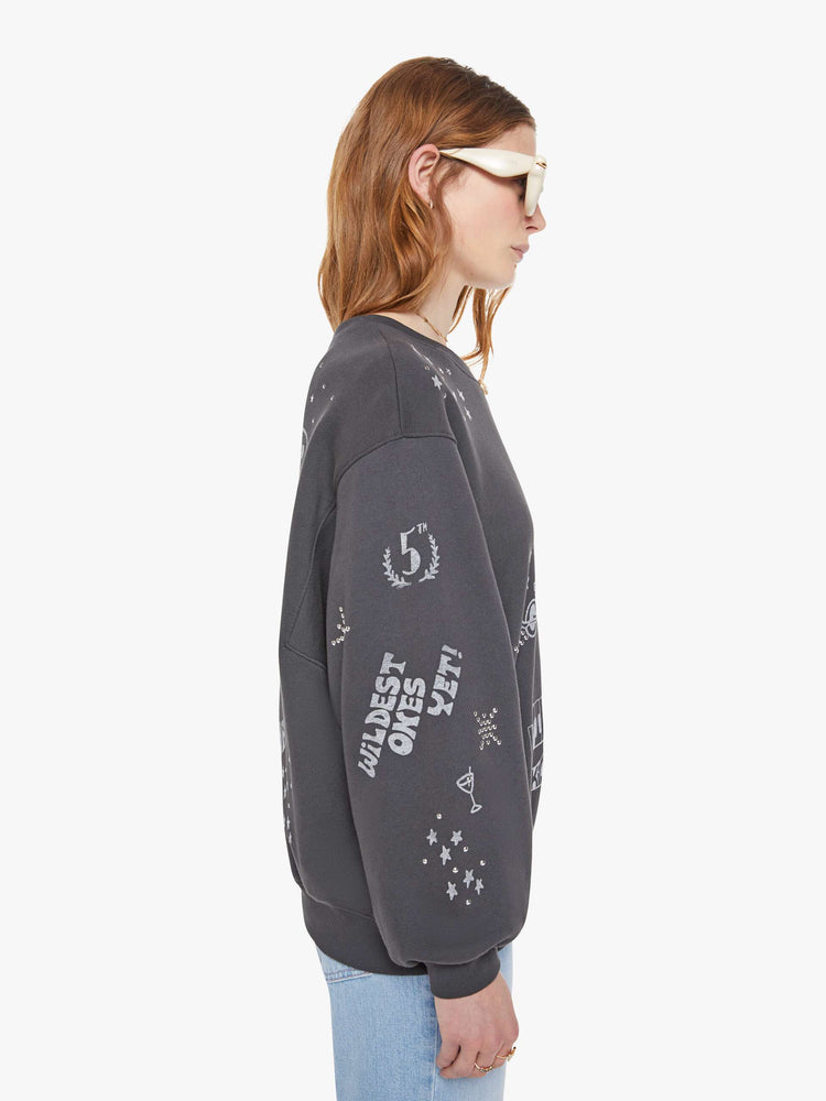Side view of a woman in a faded black oversized sweatshirt with a crewneck, drop shoulders, inset balloon sleeves and a relaxed fit