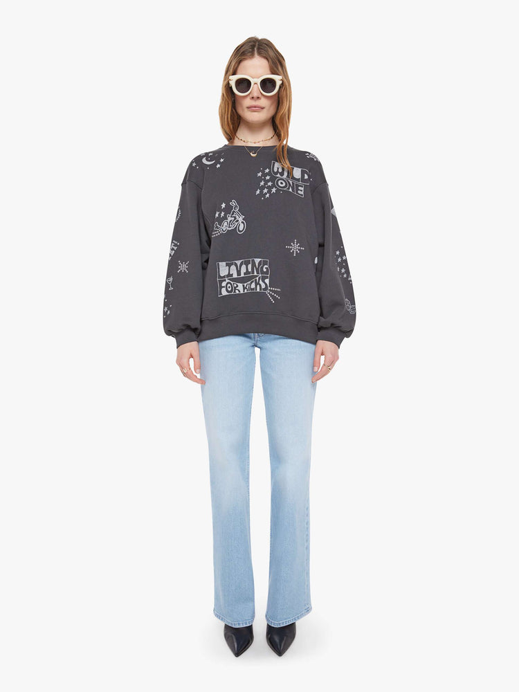 Full body view of a woman in a faded black oversized sweatshirt with a crewneck, drop shoulders, inset balloon sleeves and a relaxed fit