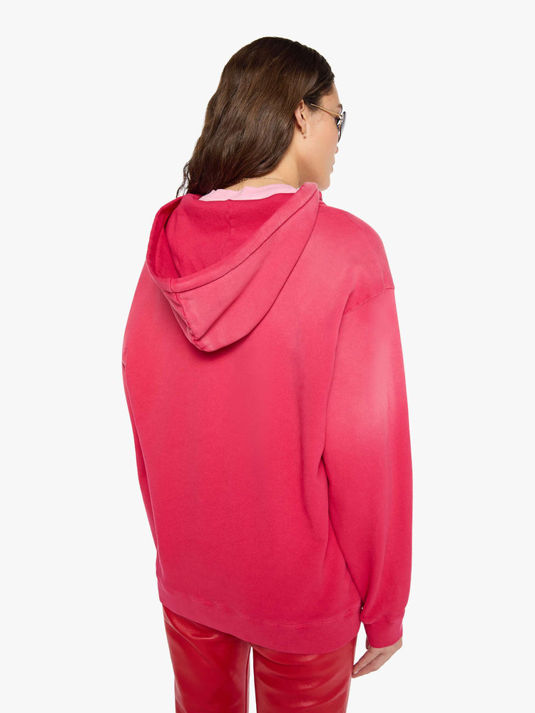Back view of a woman in a hoodie is designed in hot pink with sun fading across the shoulders and MOTHER's name in faded black text on the front.