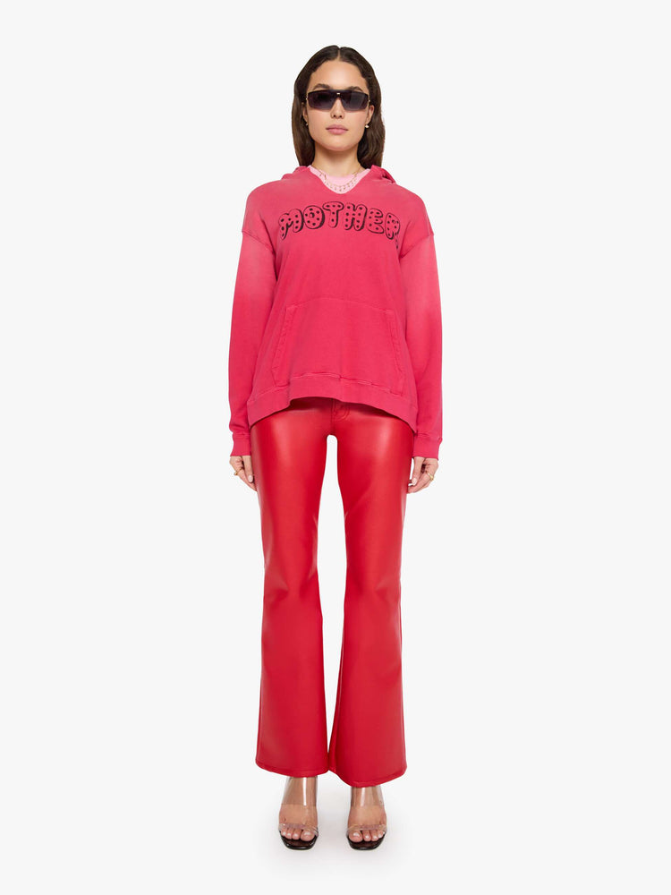 Full body view of a woman in a hoodie is designed in hot pink with sun fading across the shoulders and MOTHER's name in faded black text on the front.