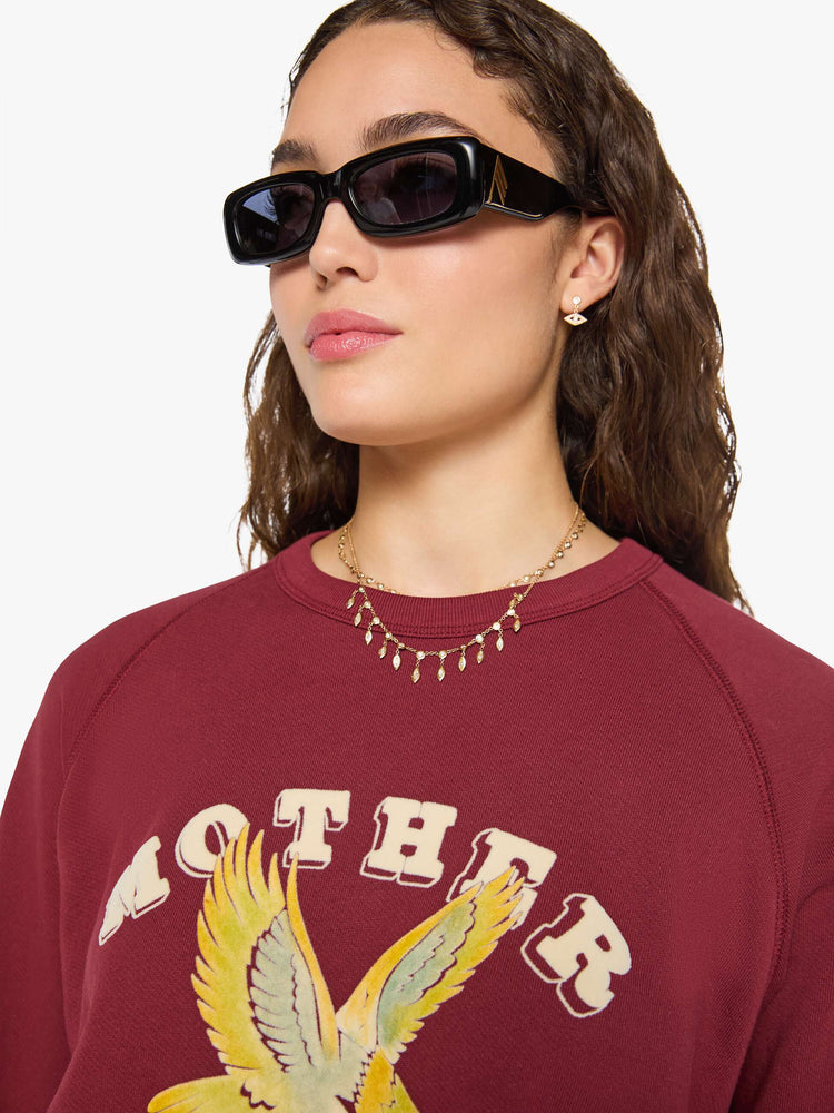 Close up view of a woman in a maroon with MOTHER's name in cream and a pastel eagle graphic in fuzzy puff print sweater.