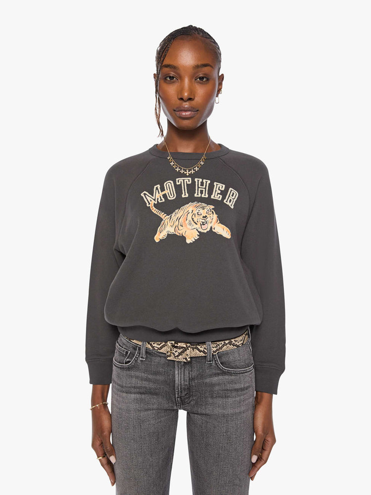 Front view of a woman in a washed black, the sweatshirt features an off-white flocked text graphic with a leaping tiger across the front.
