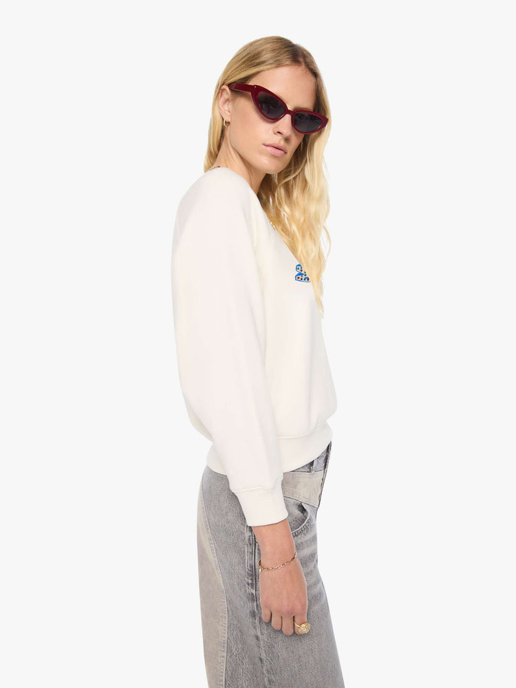 Side view of a woman in off-white with MOTHER's name in blue block text across the chest, studded details and golden yellow stars on the back sweatshirt.