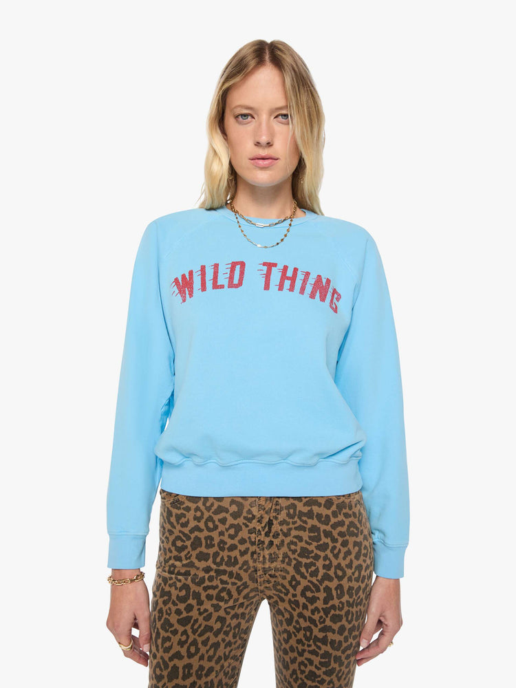 Front view of a woman in a light blue sweatshirt features a faded text graphic in red across the front.