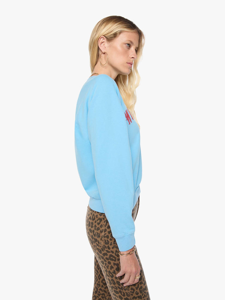 Side view of a woman in a light blue sweatshirt features a faded text graphic in red across the front.