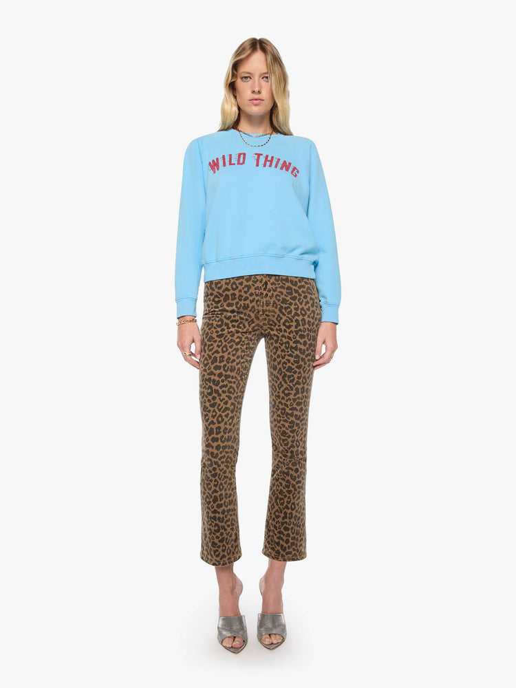 Full body view of a woman in a light blue sweatshirt features a faded text graphic in red across the front.