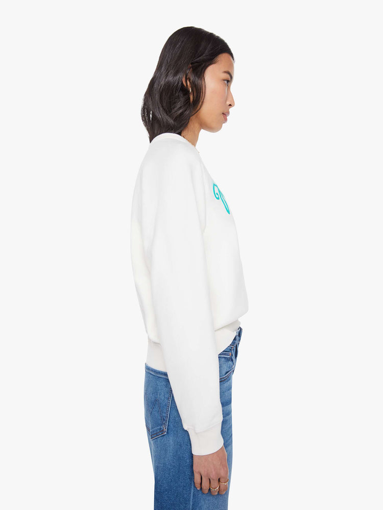 Side view of a woman in a white with sweatshirt with a crewneck, ribbed hems and a slightly oversized fit.