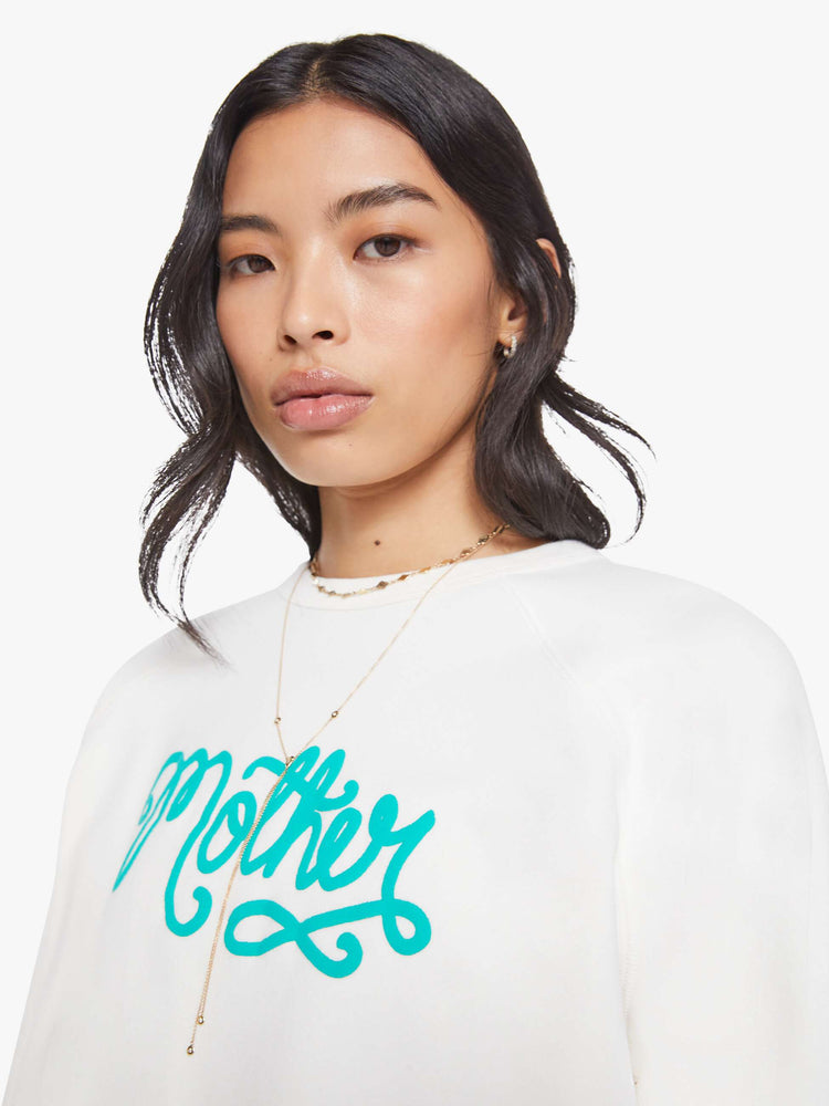 Close up view of a woman in a white with sweatshirt with a crewneck, ribbed hems and a slightly oversized fit.