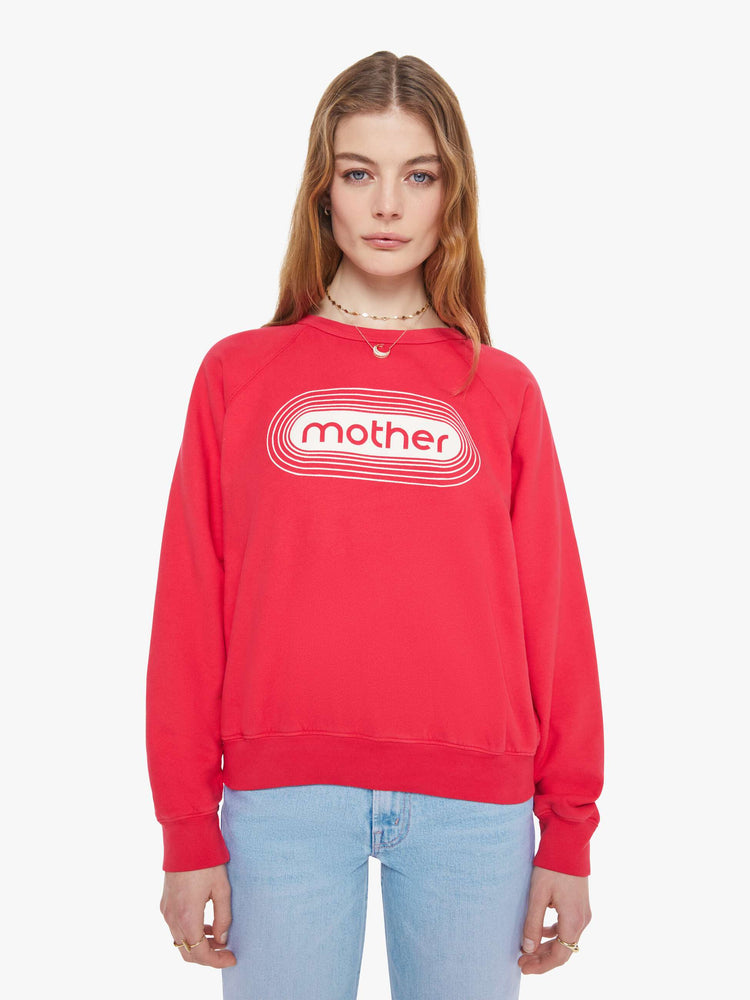 Front view in a woman in a crewneck sweatshirt in red with a white text graphic and MOTHER's name on the front.
