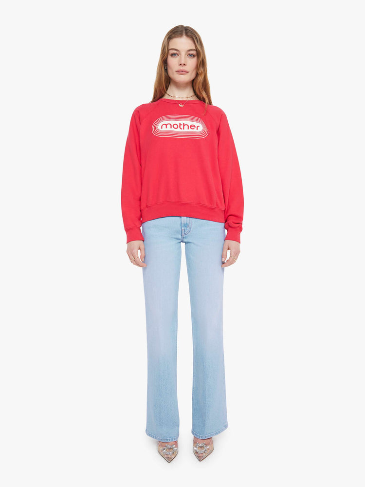 Full body view in a woman in a crewneck sweatshirt in red with a white text graphic and MOTHER's name on the front.